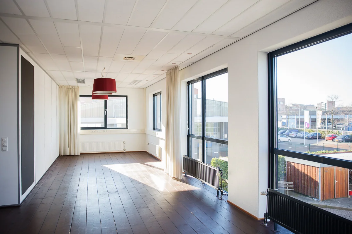 Licht en leeg kantoorruimte aan de Laan van ’s-Gravenmade met grote ramen en houten vloer.